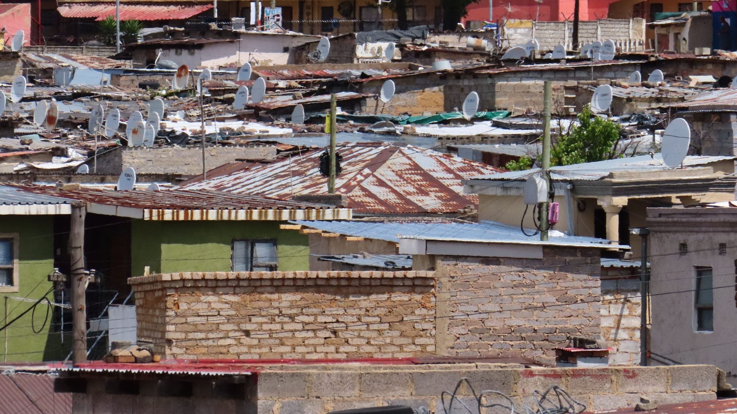 Close-set homes of brick and corrugated iron in Alexandra, satellite dishes on almost every roof.