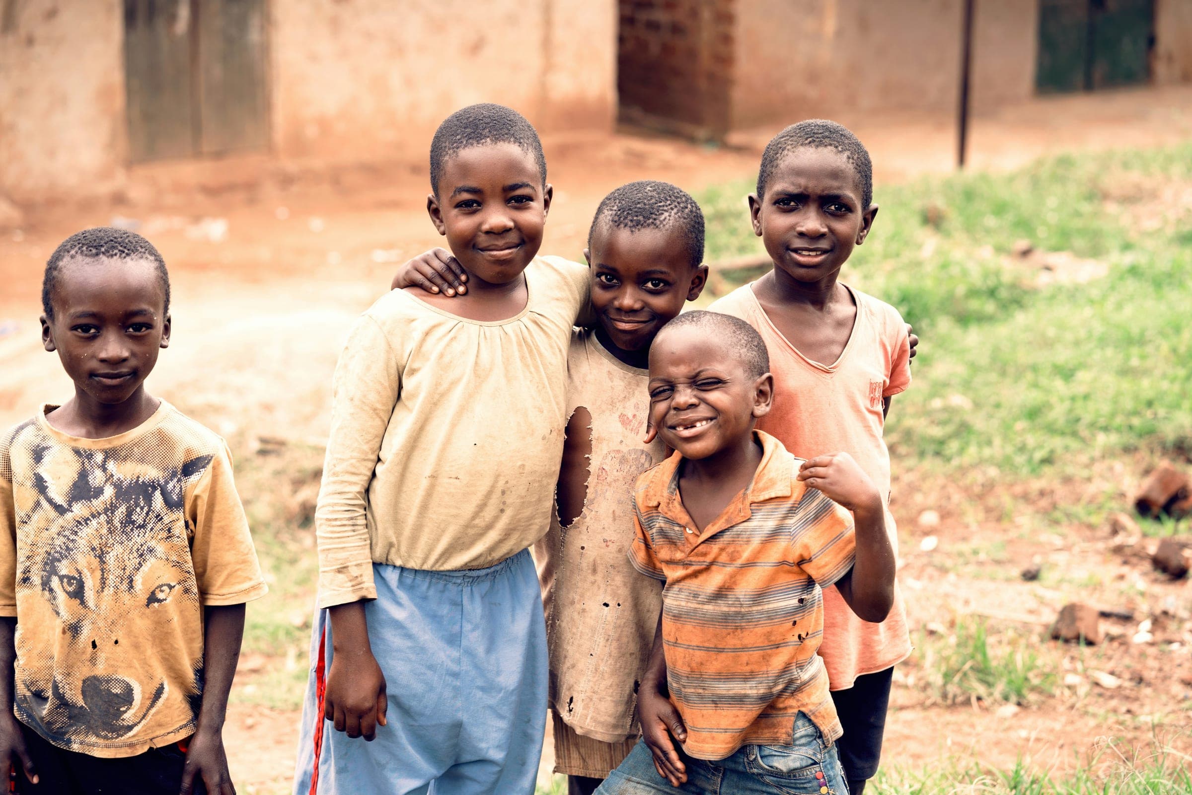 Five children standing shoulder to shoulder outside, smiling toward the camera.
