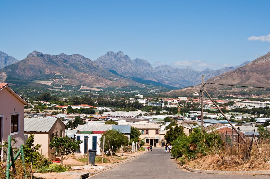 A Kayamandi street climbing the hill, homes on both sides and the Simonsberg range across the valley.