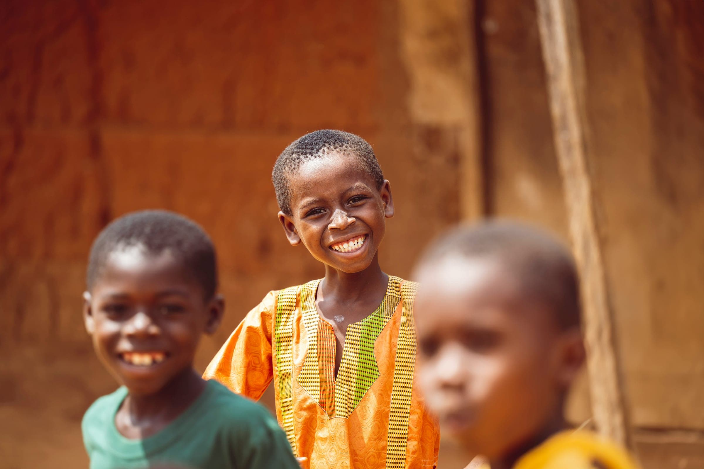 Three children standing close together, the one in the middle grinning at the camera.